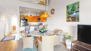 Ein modernes Wohnzimmer mit Essbereich, Küche und einem Balkon.