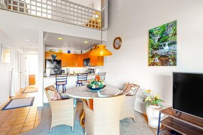 A modern kitchen with wooden cabinets, a dining area with wicker chairs, and a large window overlooking the interior. - *NEW* Fall Sale Kihei 2BR Retreat by Kamaole III with Heated Pool (Kihei)