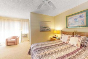 Ein Hotelzimmer mit Bett, Stuhl, Lampe und Bildern an den Wänden.