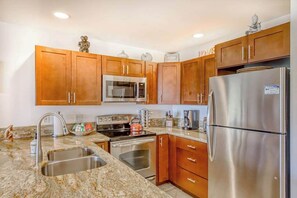 A kitchen with wooden cabinets, stainless steel appliances, granite countertops, and a built-in oven. - *New* Fall Deal Two-Level Kihei 2BR with Loft and Three Lanais (Kihei)