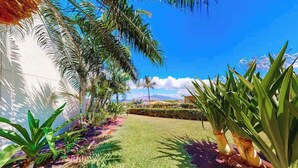Un jardin bien entretenu, agrémenté d’une variété de plantes tropicales, une pelouse parfaitement taillée et une vue dégagée sur le ciel.
