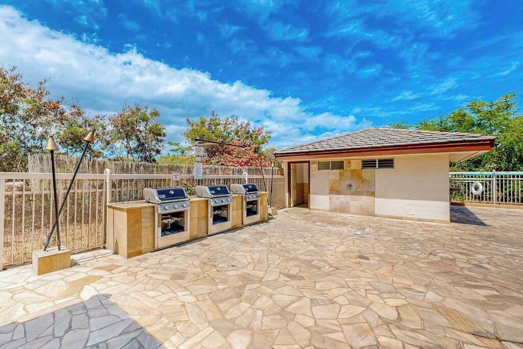 Eine Terrasse im Freien mit Steinböden, einem Grill und einem kleinen Gebäude mit einem Ziegeldach.