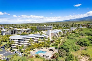 Un complejo hotelero con varias edificaciones, una piscina y zonas verdes circundantes.