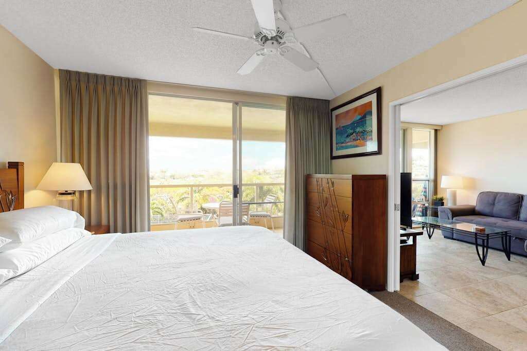Une chambre d’hôtel avec un grand lit, un ventilateur de plafond, un balcon avec vue, un canapé et une télévision.