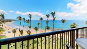 A balcony with a view of a beach, palm trees, and the ocean. - NEW Ocean-View Keawakapu Beach Suite for Four (Kihei)