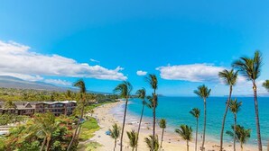 A beach resort with palm trees, a sandy beach, and a view of the ocean. - NEW Ocean-View Keawakapu Beach Suite for Four (Kihei)