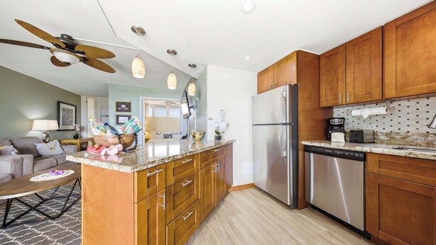 A modern kitchen with wooden cabinets, stainless steel appliances, and pendant lighting. - *New* Fall Special Oceanfront Honokōwai Retreat with a Spacious Lanai (Lahaina)