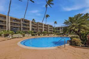 Ein Hotel mit Swimmingpool, umgeben von Palmen und Liegestühlen.