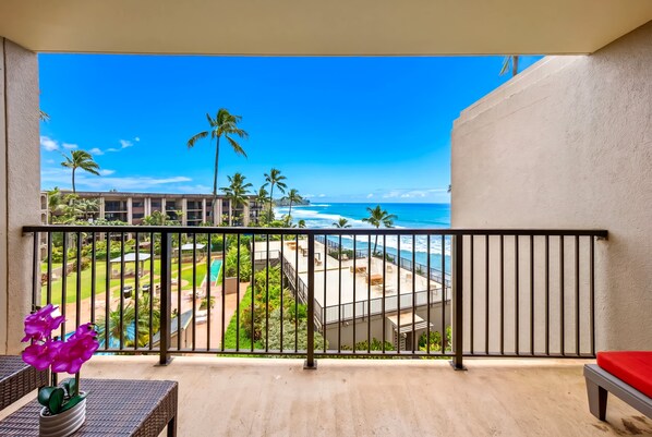 A balcony with a view of a pool, palm trees, and the ocean. - *New* Fall Special Oceanfront Honokōwai Retreat with a Spacious Lanai (Lahaina)