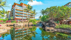 Ein Hotel mit mehreren Balkonen, einem Pool mit Felsen und tropischer Vegetation.
