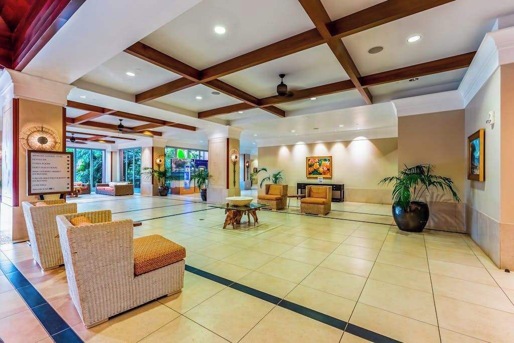 A spacious lobby with wicker furniture, a reception desk, and a large potted plant.