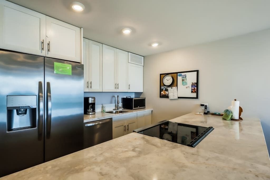 A kitchen with stainless steel appliances, a water dispenser, a microwave, and a sink.