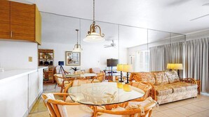 A spacious living area with a round glass table, wicker chairs, a sofa, and a television. - *NEW* Fall Deal Kihei Condo for Four with Pools and Tennis by Kamaole III (Kihei)