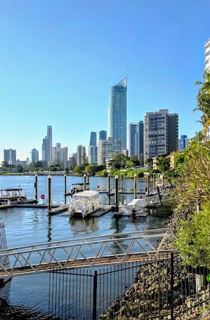 A marina with boats docked, a bridge, and a city skyline in the background. - Gold Coast Penthouse Retreat - Where every window is a view! (Surfers Paradise)