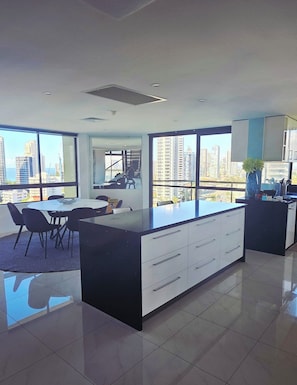 Una cocina moderna con una isla grande, comedor y ventanas amplias con vista a la ciudad.