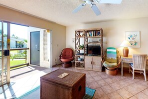 A living room with a television, wicker furniture, and a bookshelf. - *New* Fall $ale Kamaole III Beach Days with a Kihei Lanai (Kihei)