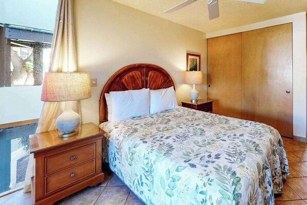 A bedroom with a bed, two bedside tables, a nightstand, a wooden wardrobe, and a ceiling fan. - *New* Fall $ale Kamaole III Beach Days with a Kihei Lanai (Kihei)