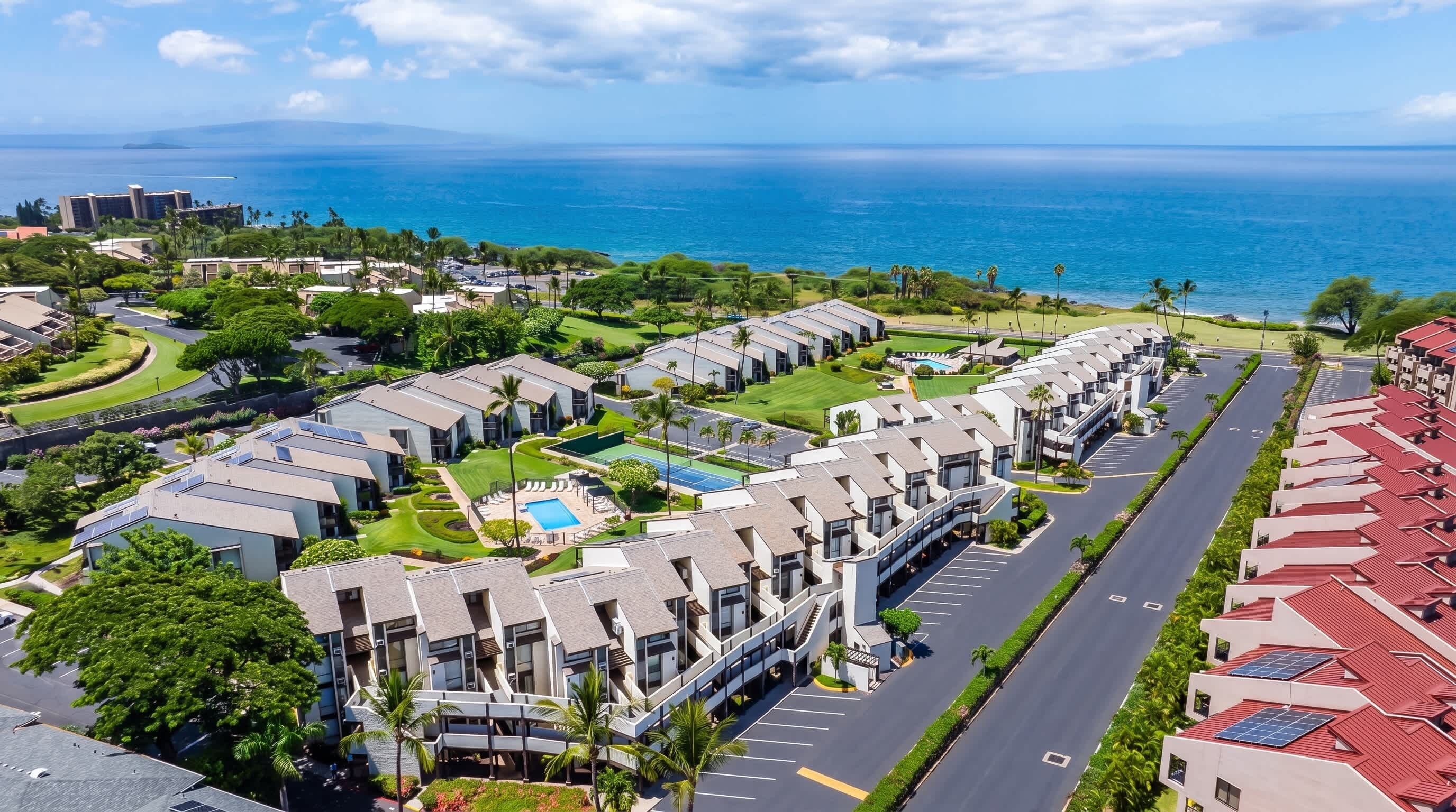 Una zona residencial moderna con piscina, cancha de tenis y vistas al océano.