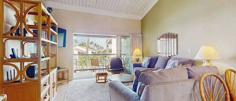 A living room with a sofa, chairs, a bookshelf, and a ceiling fan.