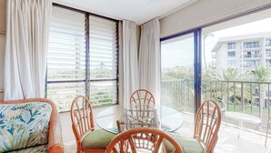 Ein Balkon mit Korbmöbeln, einem runden Glastisch und Blick auf ein Gebäude.