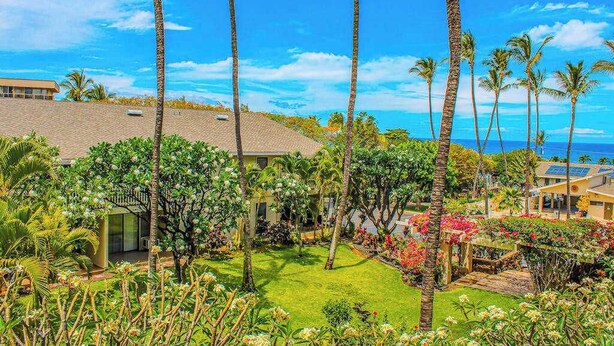 Ein Wohngebiet mit Palmen, ein Haus mit Satteldach und Blick auf das Meer.