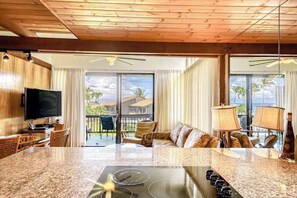 Una cocina con encimera de granito, un televisor de pantalla plana y un comedor con mesa y sillas.