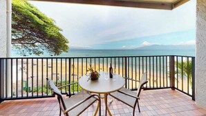 Varanda com mesa e cadeiras, com vista para a praia e o oceano.