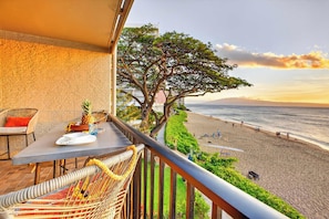 Ein Balkon mit Tisch, Stühlen und Blick auf Strand und Meer.