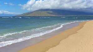 A beach with a mountain in the background, clear skies, and calm sea. - New Oceanfront Kihei Condo with Pool and Hot Tub (Kihei)