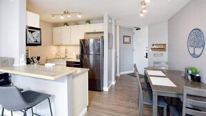A modern kitchen with a central island, stainless steel refrigerator, and white cabinetry. - New Oceanfront Kihei Condo with Pool and Hot Tub (Kihei)