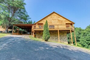 Eine Holzhütte mit Steinuntergrund, einer Veranda und einem gepflegten Rasen.