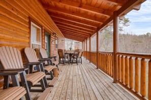 Eine Holzterrasse mit Stühlen und Tisch, einem Hollerleger und Blick auf die umliegende Landschaft.