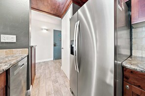 A kitchen with a stainless steel refrigerator, wooden cabinets, and a tiled backsplash. - *New* Fall Deal Oceanfront Kahana Stay, Walk to Pohaku Park (Lahaina)
