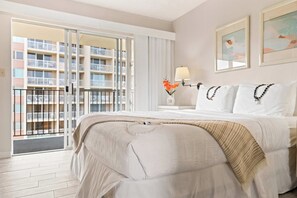 A hotel room with a bed, a nightstand, a lamp, and a view of a building through the window. - *New* Fall Deal Oceanfront Kahana Stay, Walk to Pohaku Park (Lahaina)
