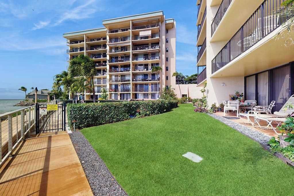 Ein mehrstöckiges Hotel mit Balkonen, einer Rasenfläche und Blick auf das Meer.