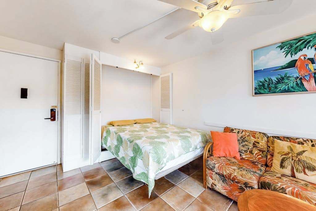 Ein Zimmer mit einem Bett, einer Schlafcouch, einem Deckenventilator und einem Bild an der Wand.