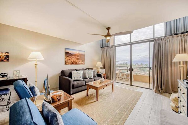 Una sala de estar moderna con sofá, una mesa de centro y un ventanal con cortinas.