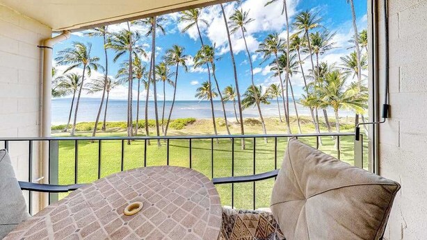 A balcony with a view of palm trees and the ocean. - New Kihei Ocean-View Retreat for Two with Beachfront Pool (Kihei)