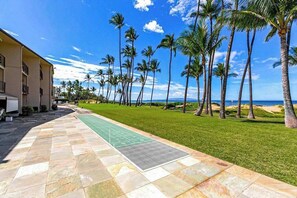 A paved walkway, a green lawn, and tall palm trees. - Ocean-View Kihei Escape for Two, Steps from the Beach (Kihei)