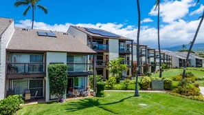 A modern hotel with multiple-story buildings, solar panels on the roofs, and well-maintained gardens with palm trees. - *New* Fall Special Garden-View Kihei Base for Four Near Kamaole III Beach (Kihei)
