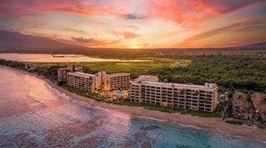 A beachfront hotel with multiple buildings, a pool, and a view of the ocean and sunset. - New Beachfront Couple’s Base at Sugar Beach (Kihei)