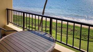 Un balcón con vista al mar, una mesa redonda y una barandilla.