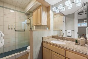 Une salle de bain moderne équipée d’une douche, de toilettes, d’un meuble-lavabo et d’un grand miroir.