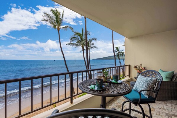 Un balcon avec vue sur l’océan, une table avec des chaises et une rambarde.