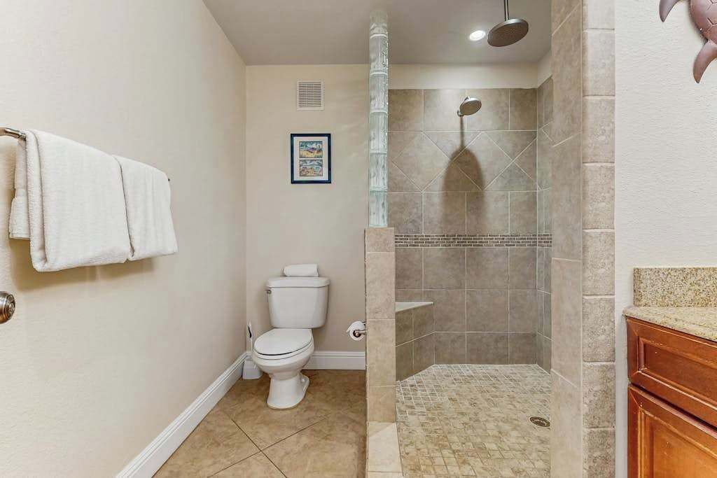 Un baño con inodoro, ducha con puerta de cristal y un perchero para toallas.