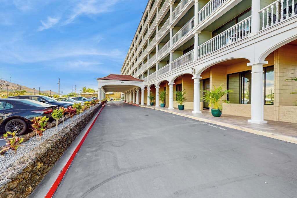 A hotel with a covered outdoor area, multiple balconies, and a parking lot.