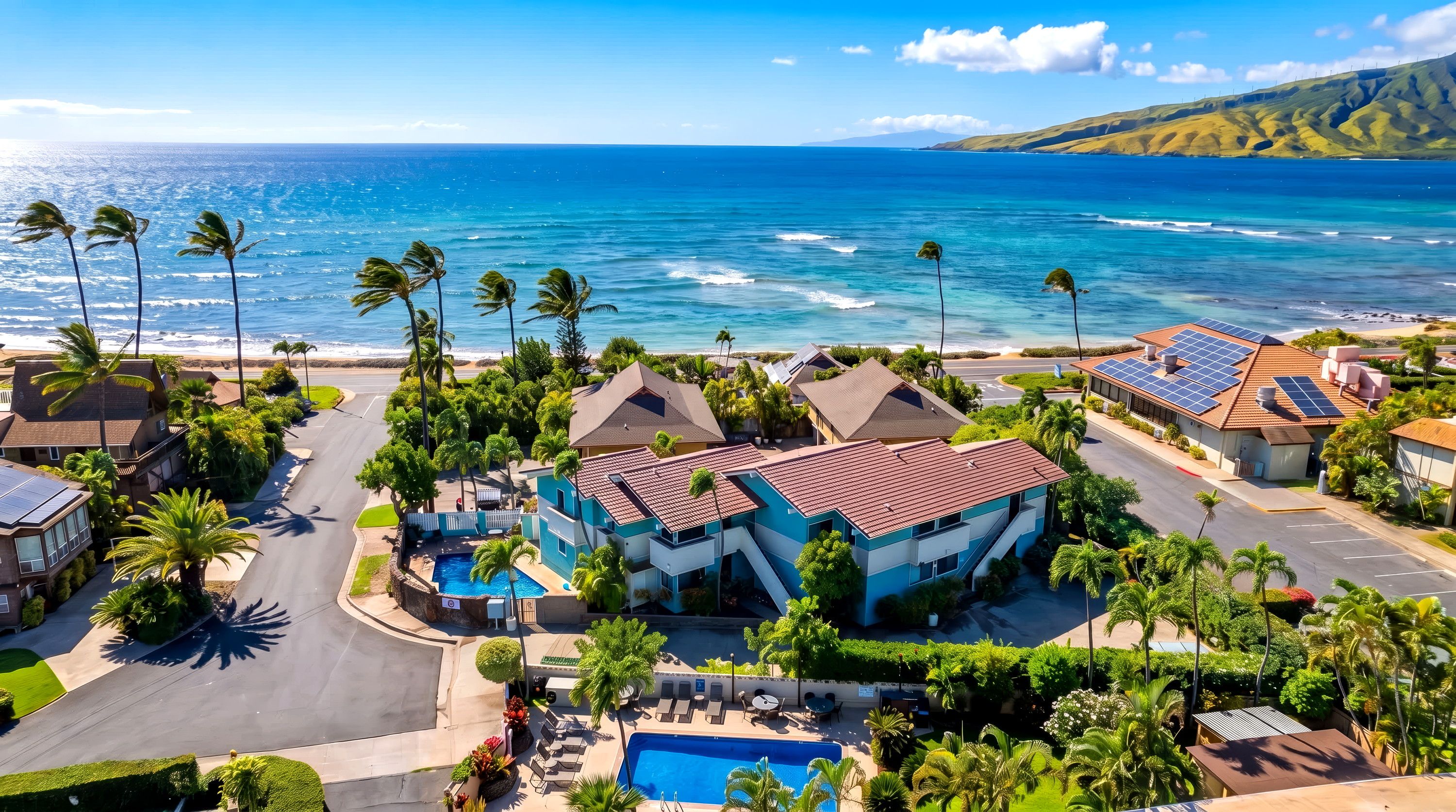A residential area with a swimming pool, solar panels, and a view of the ocean.