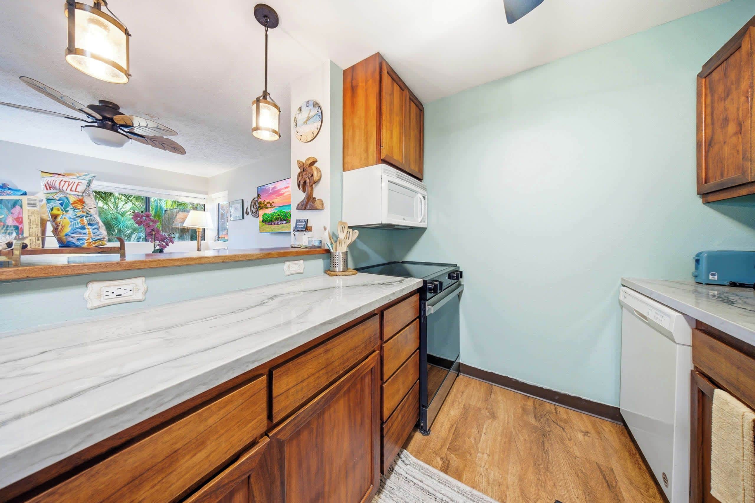 A kitchen with wooden cabinets, a white microwave, and a ceiling fan.