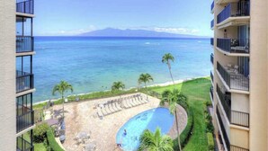 A hotel with a pool, lounge chairs, and a view of the ocean.