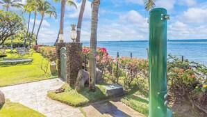 Un jardín tropical con palmeras, un muro de piedra y vista al océano.